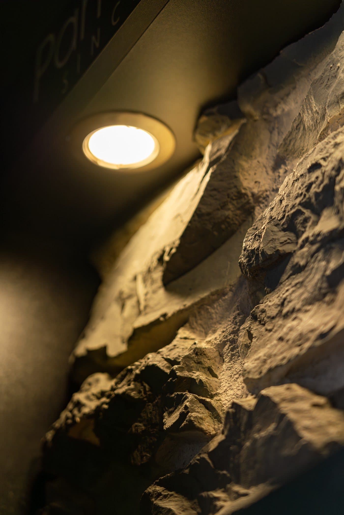Parede em pedra natural com iluminação de destaque no showroom